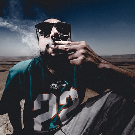 Man wearing sunglasses and smoking cigarette.